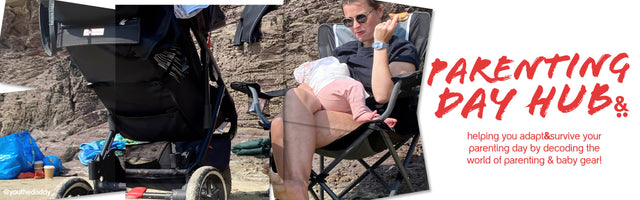 Mom sitting on a chair at the beach feeding baby with a 3 wheeled stroller in the foreground - parenting day hub -  philandteds.com
